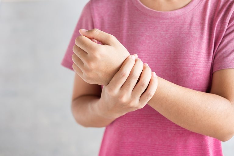 Young woman holding her wrist pain because using computer long t